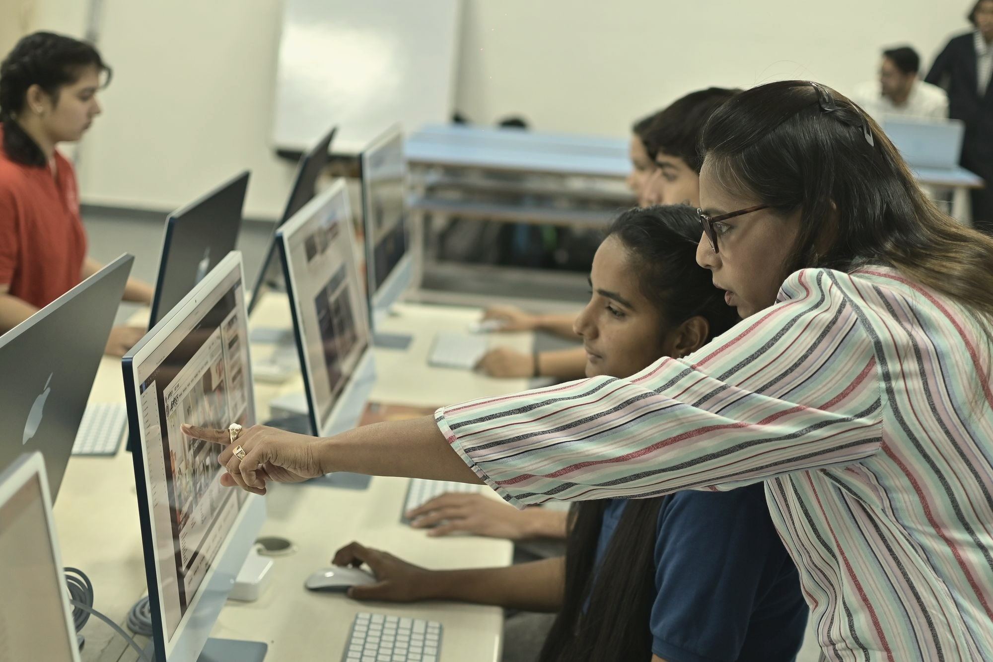An instructor guiding students at computers in a lab