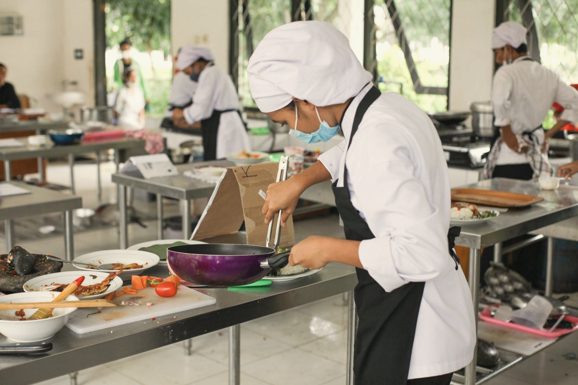 A culinary student cooking at a station in a training kitchen