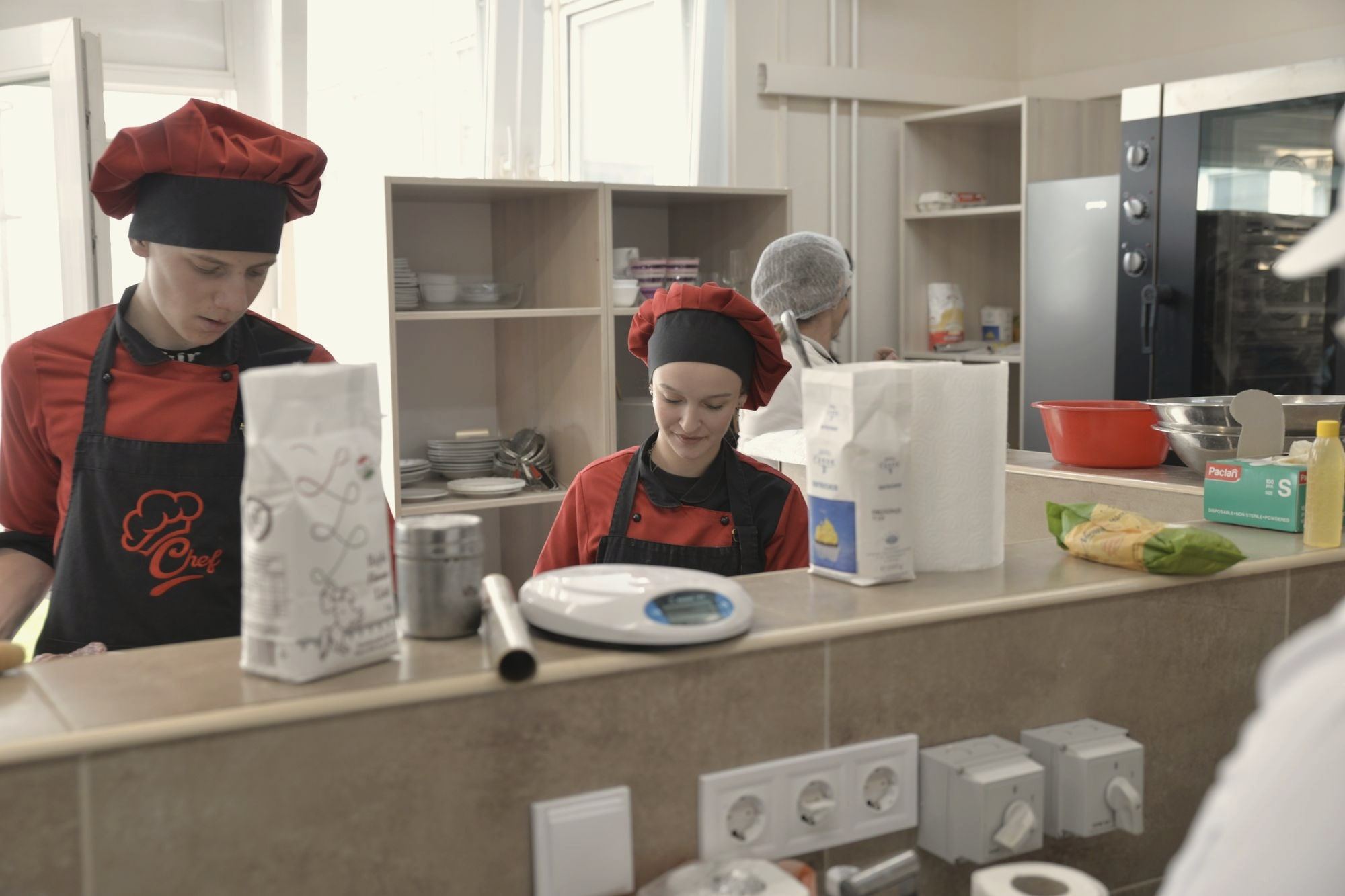 A smiling culinary student working at a station in a training kitchen