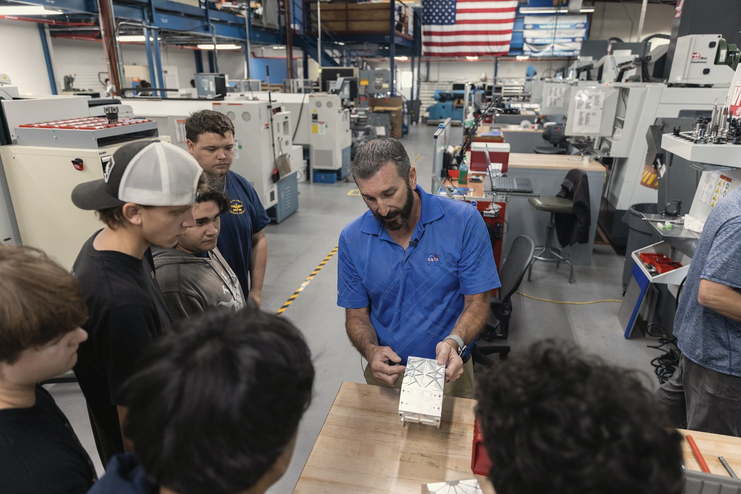 Florida high school students gathered around an instructor in the Kennedy Space Center machine shop