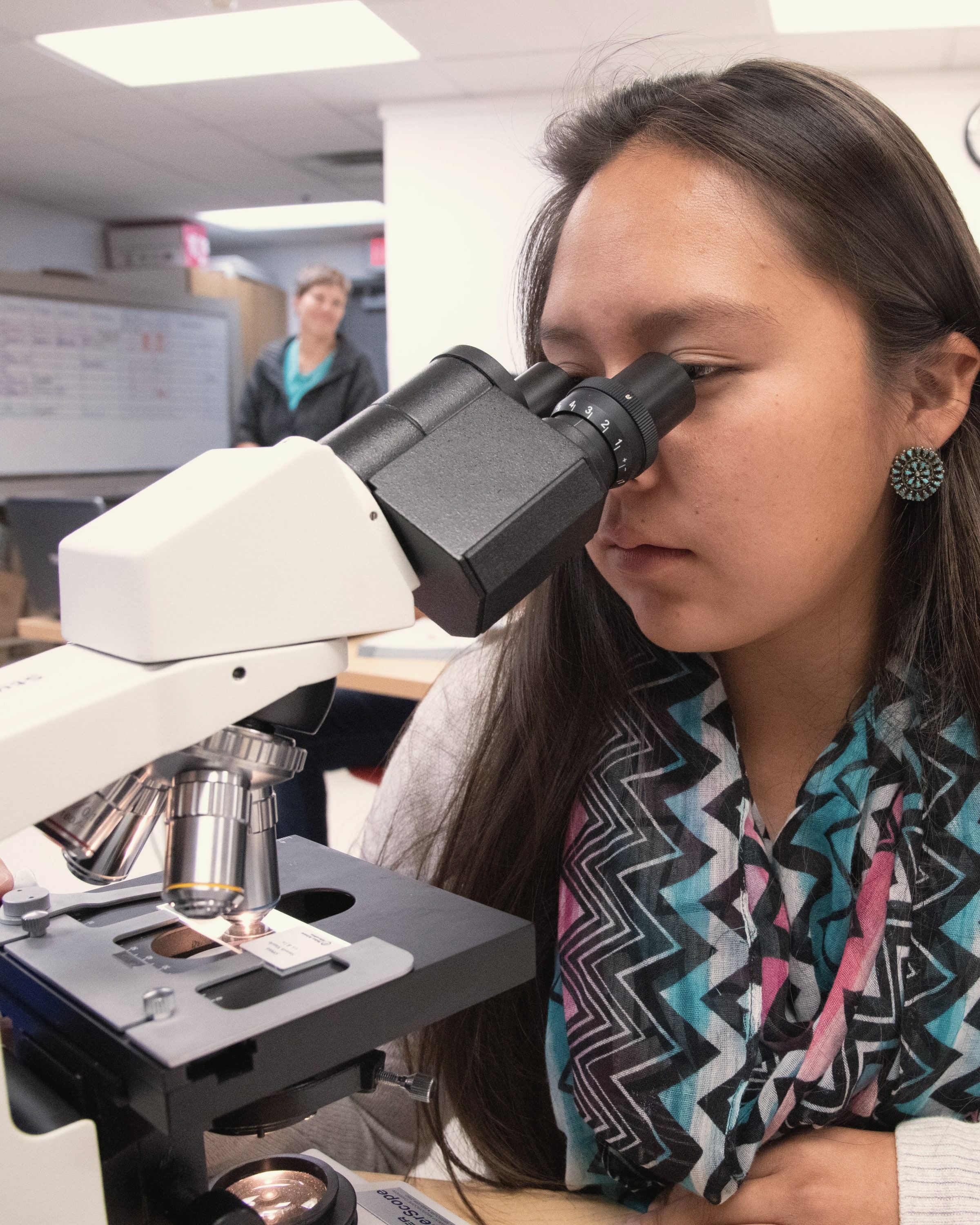 A student looking through a microscope in a teaching lab